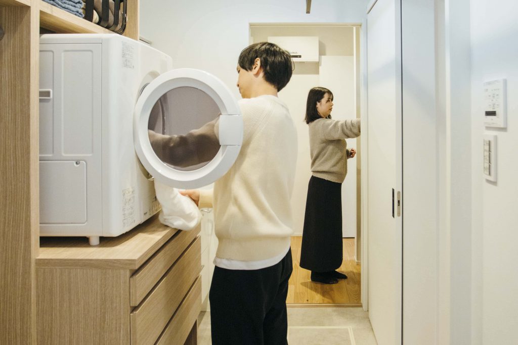 夫婦がガス乾燥機「乾太くん」を使用して洗濯物を取り込んでいる様子