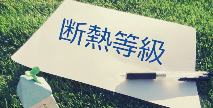 芝生の上で「断熱等級」とか書かれた紙が置かれている