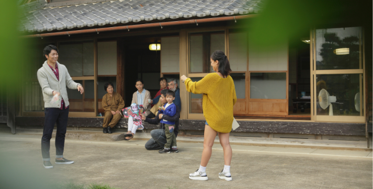家族が庭で遊ぶ様子を眺める人々