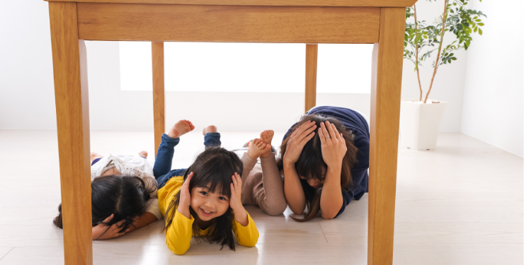 地震から身を守るため机の下に隠れる人々