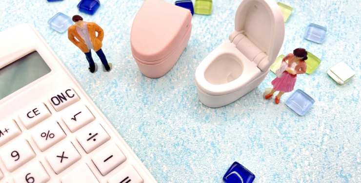 ミニチュアのトイレと人が電卓の周りに設置されている