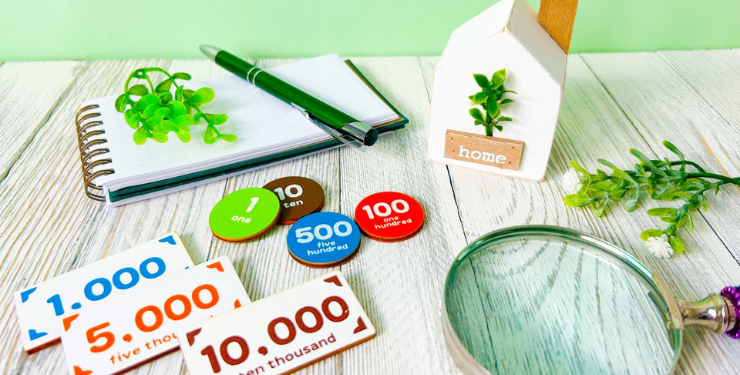 家の模型の周りにおもちゃのお金が置かれている