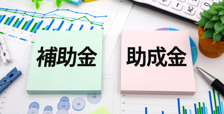 資料の上に補助金と助成金と書かれた付箋が置かれている