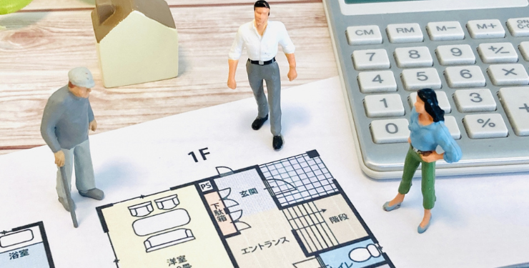 3人の模型と電卓が間取り図の上にある