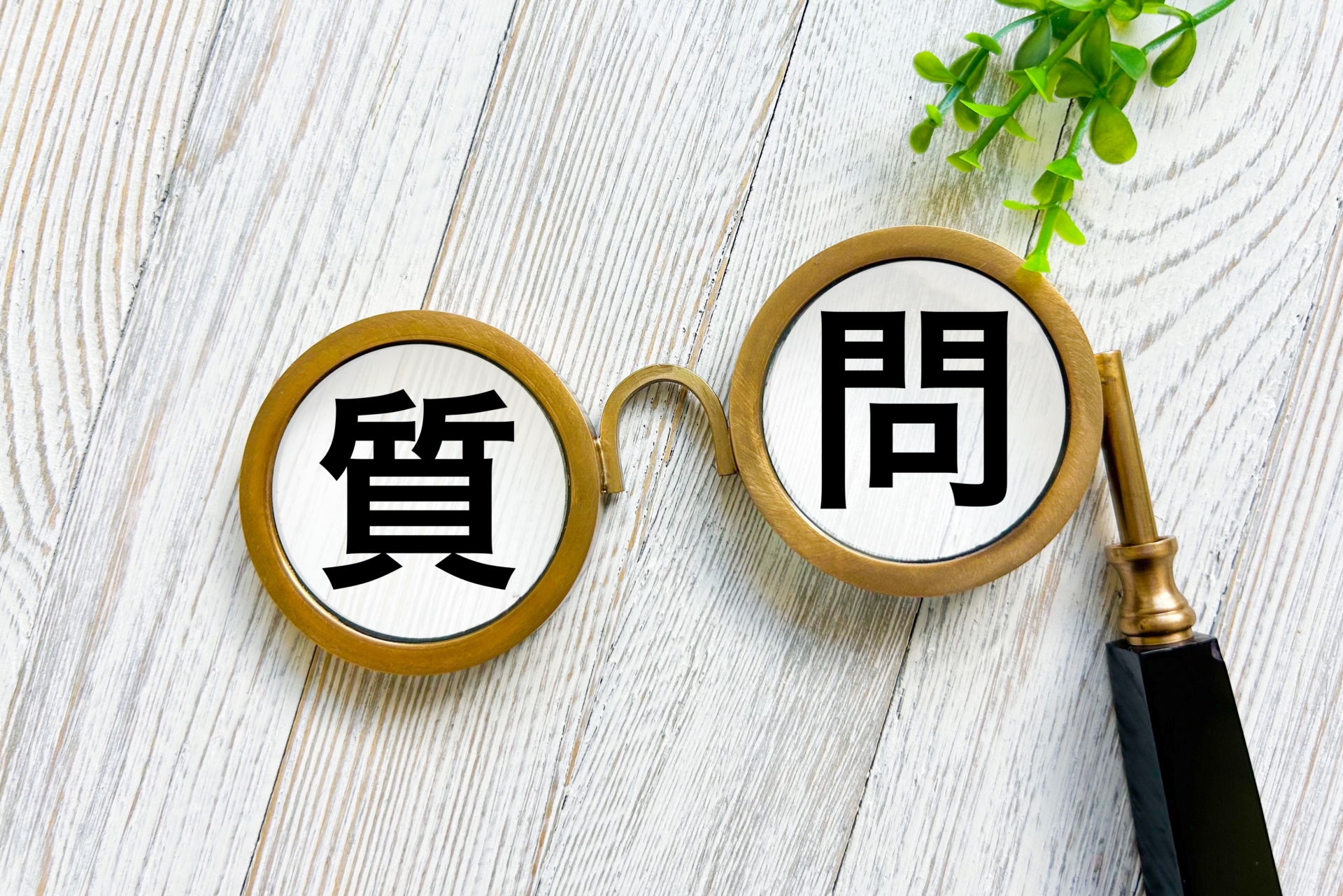 机に置かれた眼鏡の中に質問と書かれた文字が写っている