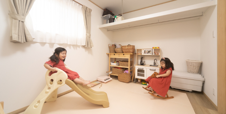 子ども部屋で姉妹が滑り台で遊んでいる様子