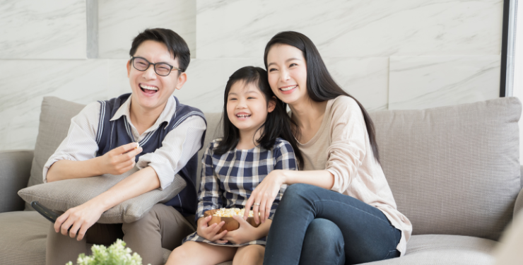 3人家族が快適な部屋でソファーに座って笑っている