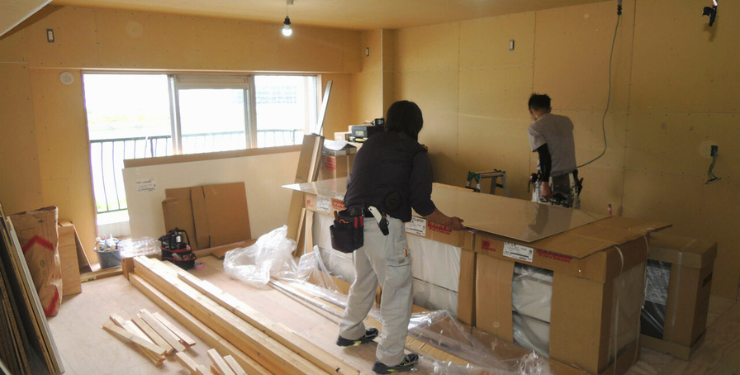マンションスケルトンリフォームので男性二人がガラス板を運んでいる様子