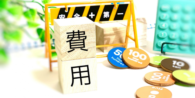 安全第一のフェンスの模型の前に費用と書かれたブロックが重なっている