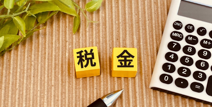 税金と書かれたブロックと電卓とペンが置かれている