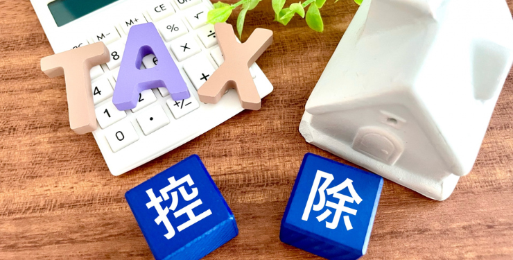 電卓の上にTAXと書かれた文字が置かれており、家の控除を表している