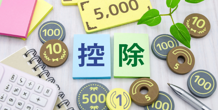 控除と書かれたパネルの周りにおもちゃのお金が置かれている