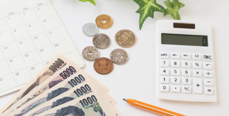 電卓とお金と鉛筆とカレンダーが置かれている