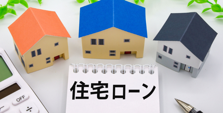住宅ローンとっ枯れたスケッチブックの周りに3軒の家の模型が並んでいる