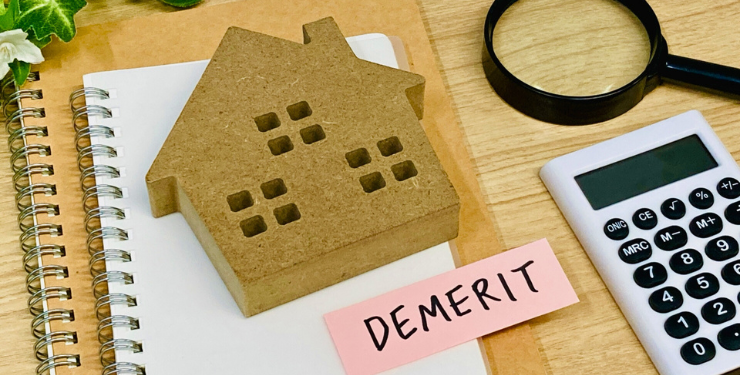 ノートの上に家のコルクパネルと「DEMERIT」と書かれた付箋が置かれており、周りに虫眼鏡と電卓が置かれている