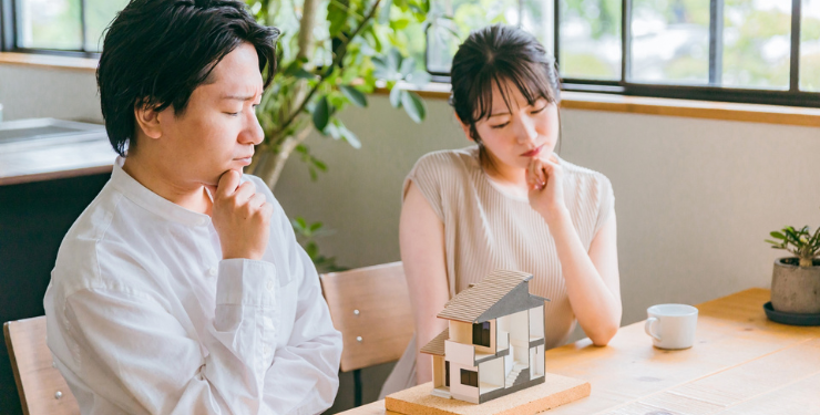 家の模型を見ながら夫婦で悩んでいる様子