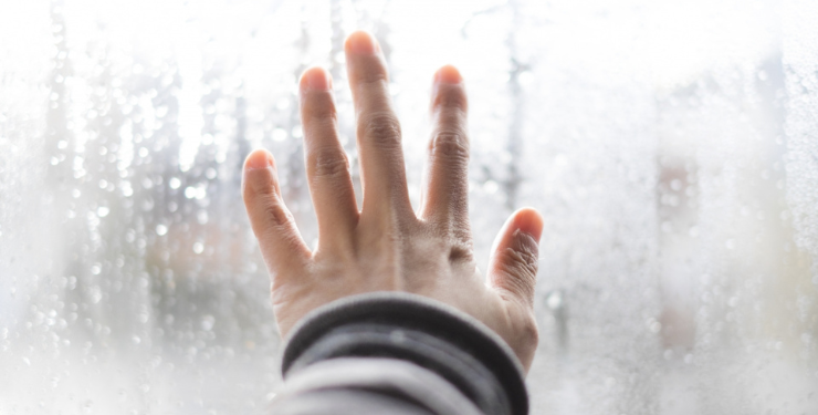 結露した窓に手を当てている様子