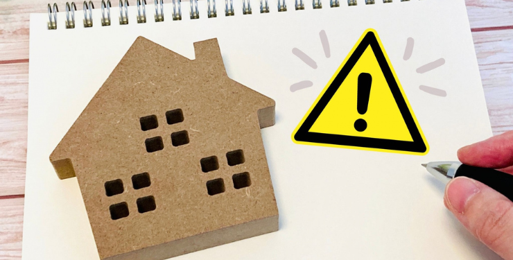 ノートの上に置かれたコルクの家のパネルの横にビックリマークが書かれている