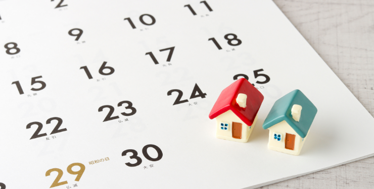 小さい家の模型がカレンダーの上に置かれている