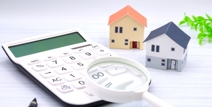 2棟の家の模型のそばに電卓と虫眼鏡がある