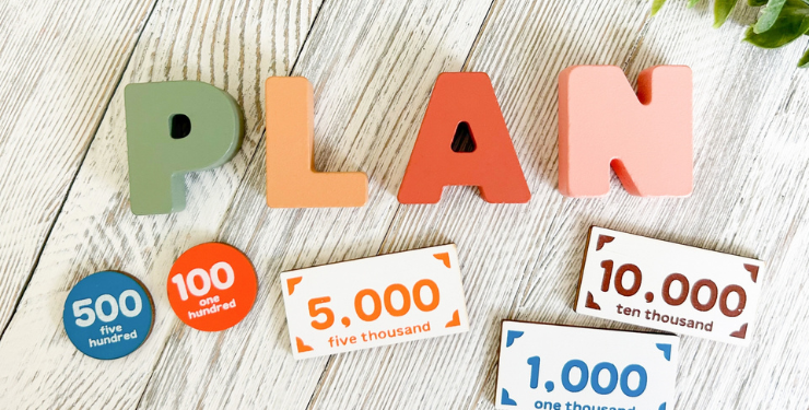 PLANと書かれたロゴの周りにおもちゃのお金が置かれている